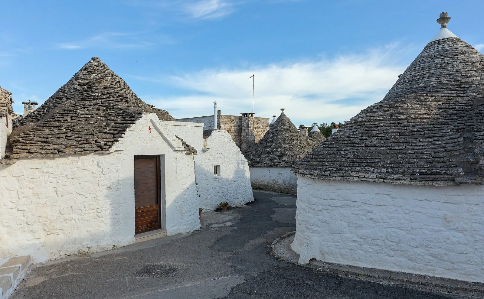 Una stradina del Rione Aia Piccola ad Alberobello tra trulli dai muri bianchi e dai tetti conici in pietra grigia