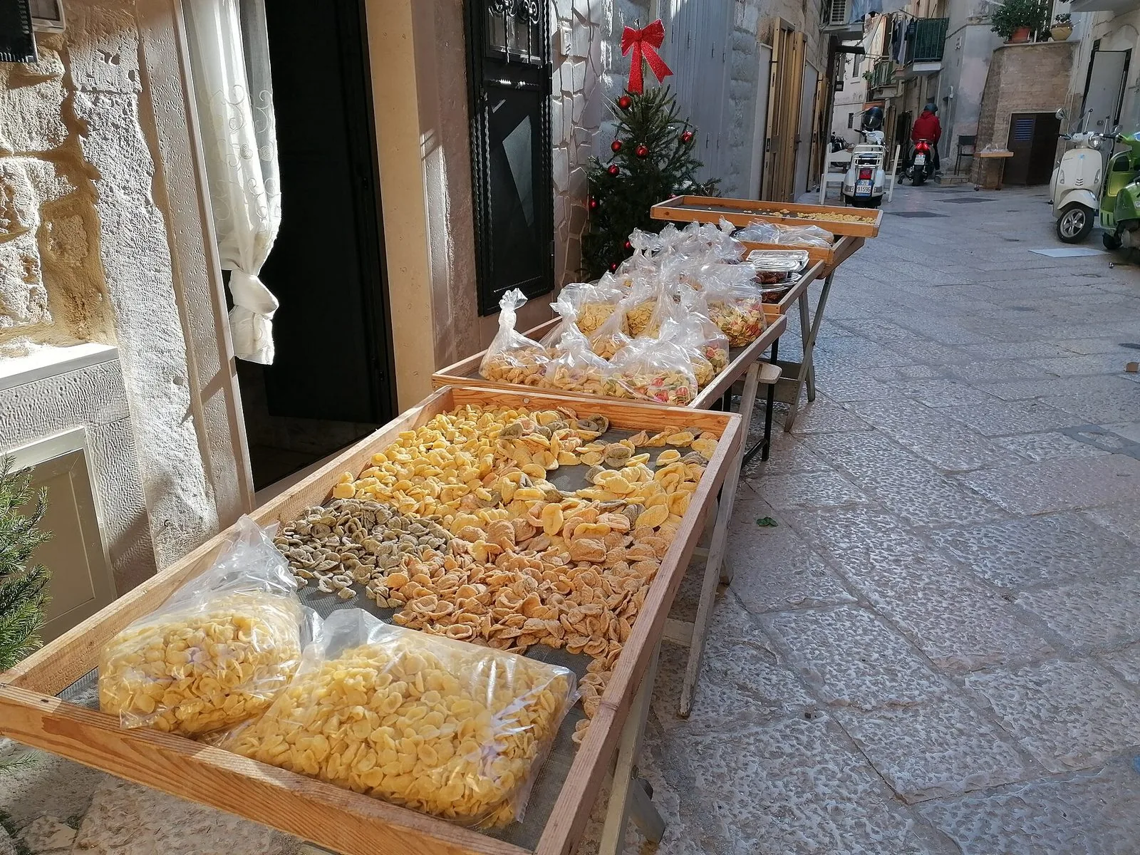 Telai di legno con orecchiette fresche messe ad asciugare e sacchetti di pasta lungo un vicolo lastricato di Bari Vecchia