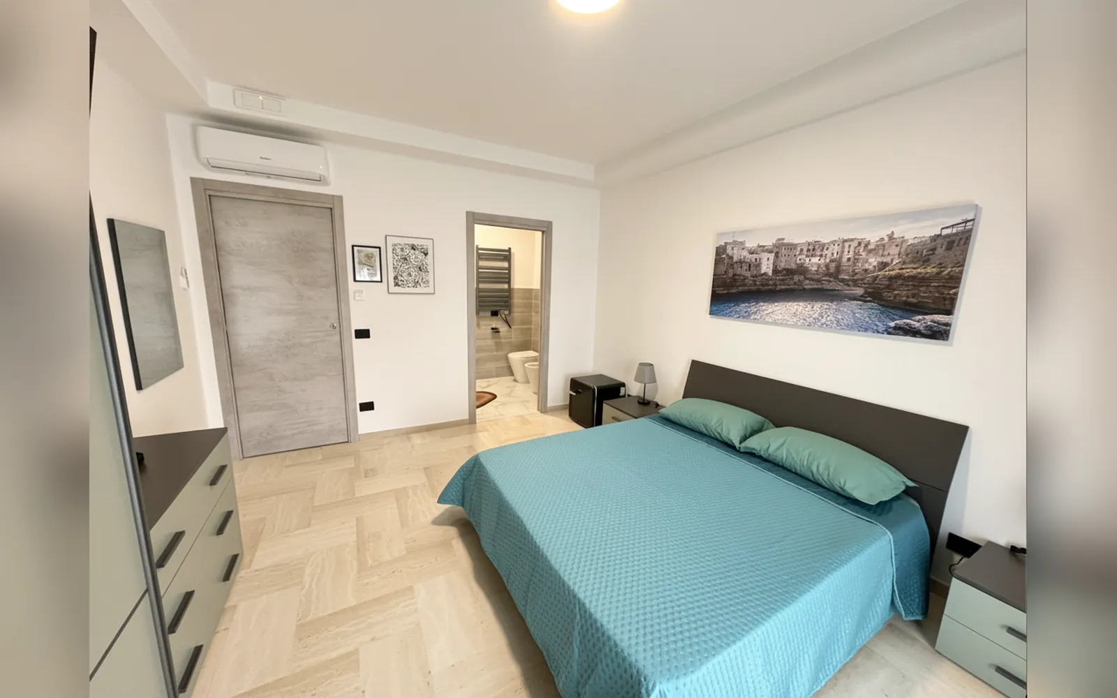Il letto matrimoniale, la porta del bagno privato e il quadro con il mare